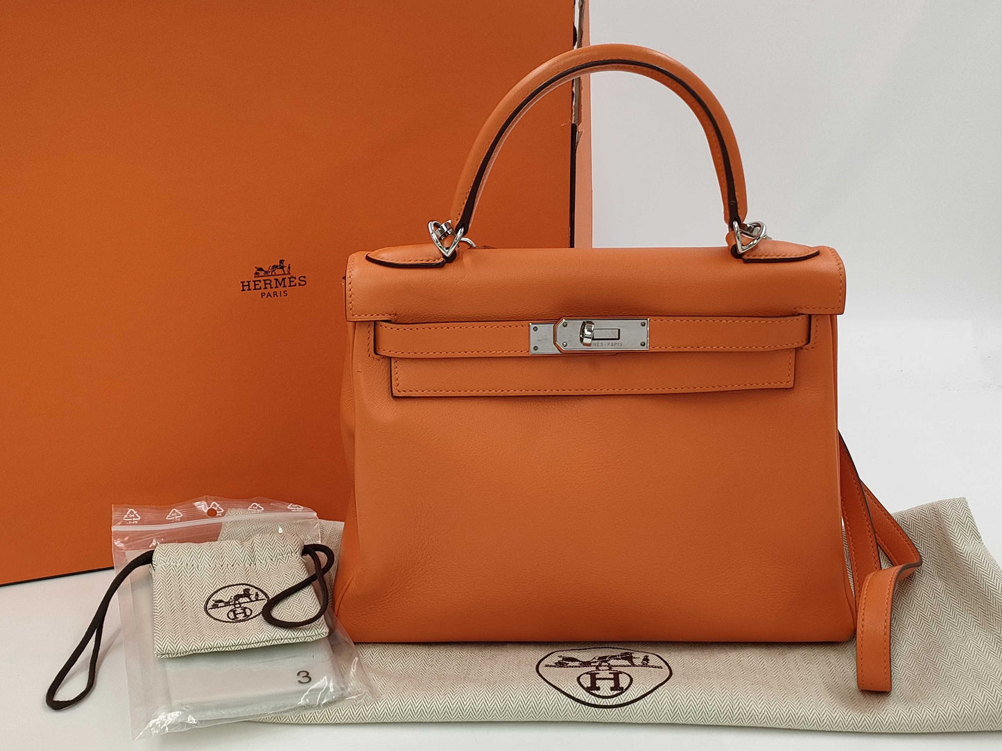 HERMES Kelly 28 handbag with silver hardware, inner stitching, orange Taurillon leather, K stamped.